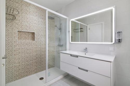 ein weißes Badezimmer mit Waschbecken und Dusche in der Unterkunft Apartamento Jardins da Falésia in Albufeira