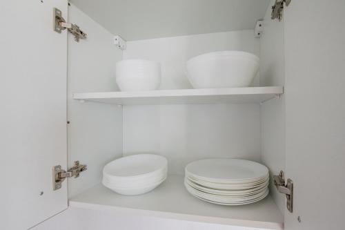 two white plates and bowls in a white cabinet at Tolstov Apartments - 3 Room Apartments with Garden - 20 Min Messe DUS & Airport DUS in Meerbusch