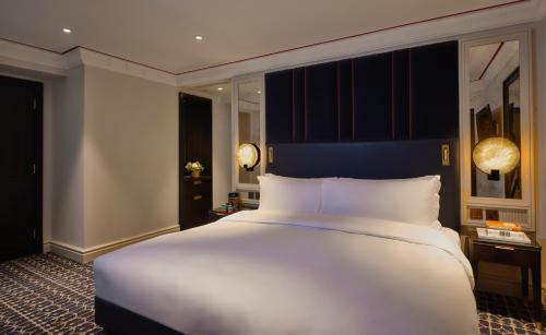 a large white bed in a hotel room at The Mayfair Townhouse - an Iconic Luxury Hotel in London