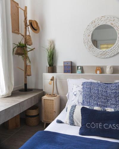 a bed with blue and white pillows and a mirror at Hotel de La Plage - Mahogany in Cassis