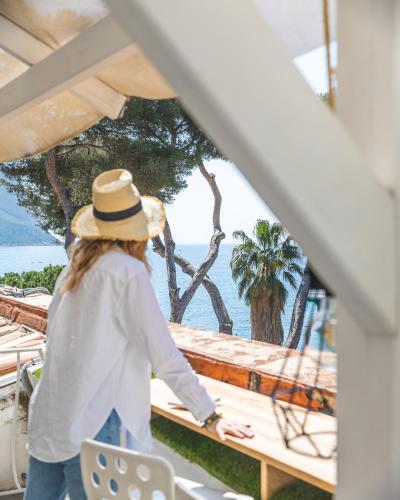 a woman in a straw hat walking out of a boat at Hotel de La Plage - Mahogany in Cassis