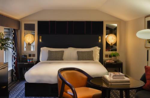 a bedroom with a bed and a table and a chair at The Mayfair Townhouse - an Iconic Luxury Hotel in London