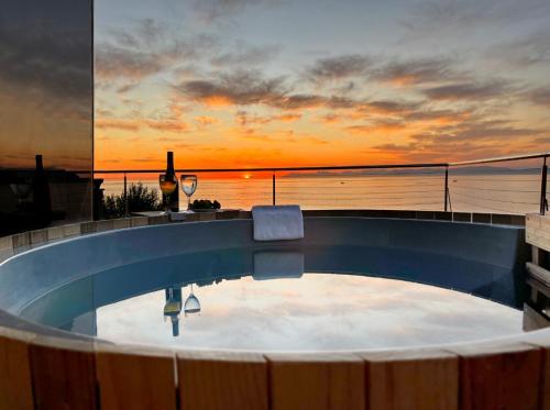 a swimming pool with a sunset in the background at Whale Huys Luxury Oceanfront Eco Villa in Gansbaai
