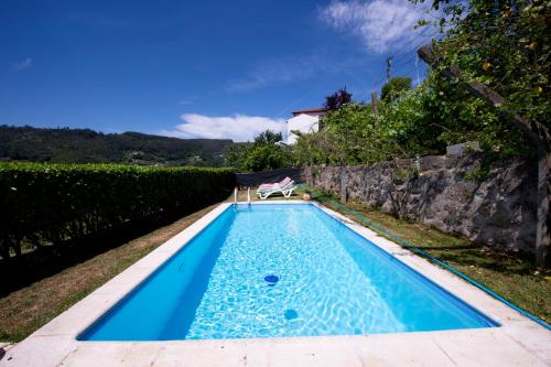 una piscina azul con una silla en un patio en Casas do Casinhoto - Casa do Cabo, en Baião