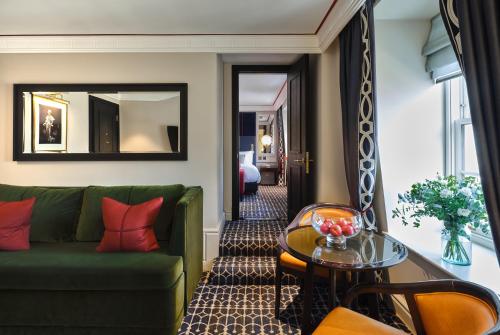 a living room with a green couch and a table at The Mayfair Townhouse - an Iconic Luxury Hotel in London