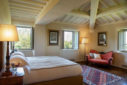 a bedroom with a large bed and a red chair at Il Borro Relais & Châteaux in San Giustino Valdarno