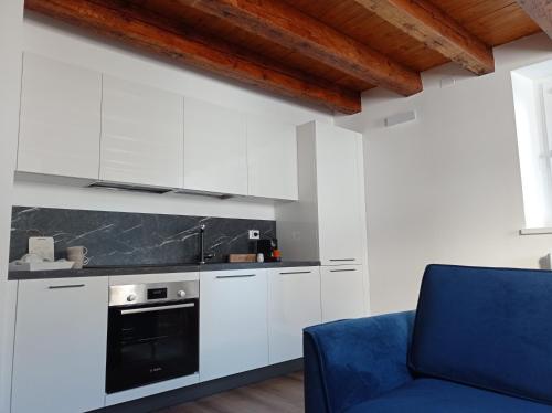 a kitchen with white cabinets and a blue chair at Sarpi21 Suites in Udine