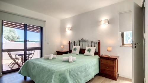 a bedroom with a green bed and a balcony at Villa Palmeira Galé Beach in Albufeira