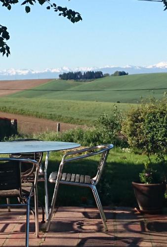 a table and chairs with a view of a field at Maison avec vue Pyrénées et piscine chauffée in Aignes