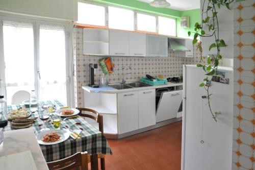 una cocina con armarios blancos y una mesa con comida. en Casa Serena, en Ivrea