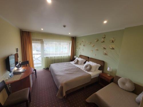 a hotel room with a bed and a desk and a computer at Hotel Green Smiltynė in Panevėžys