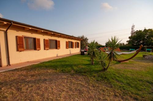 a house with a hammock next to a yard at Agriturismo L'Istrice di Giò in Montalto di Castro