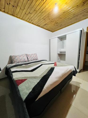 Bett in einem Schlafzimmer mit Holzdecke in der Unterkunft Cantinho do Nono 2 in Campos do Jordão