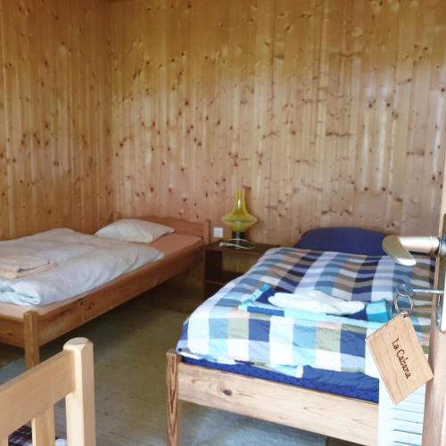 a bedroom with two beds in a wooden wall at Kerca Bio Farm in Kercaszomor