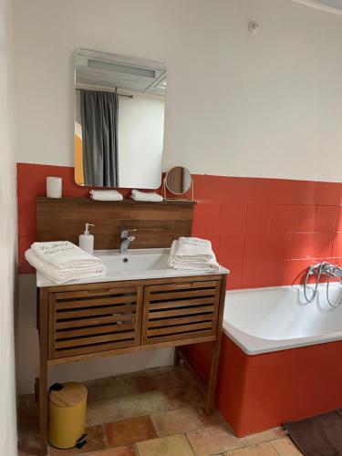 a bathroom with a sink and a tub and a mirror at Le Petit Egregore, patio et climatisation in Lauris