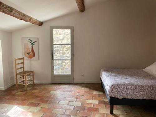 a bedroom with a bed and a window and a chair at Le Petit Egregore, patio et climatisation in Lauris