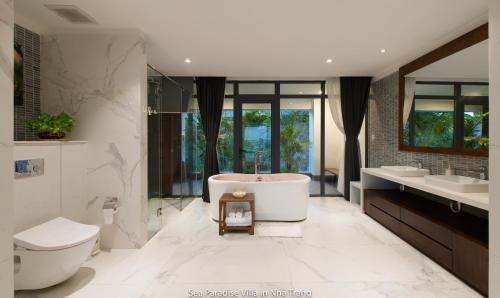 La salle de bains est pourvue d'une baignoire, de deux lavabos et de toilettes. dans l'établissement La Nha Trang Villa by Elite Stay, à Nha Trang