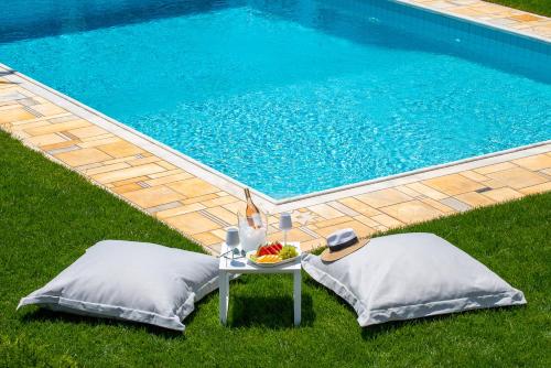a table and pillows next to a swimming pool at Kamariyo Athens Riviera by A&D Properties in Palaia Fokaia