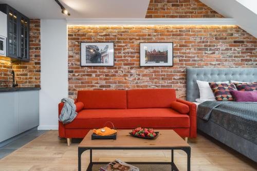 a living room with a red couch and a brick wall at Saint Florian's Suites - Old Town Luxury Apartments - by Upstairs in Kraków