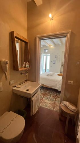 a bathroom with a sink and a toilet and a bed at Antico Mondo Rooms & Suites in Polignano a Mare