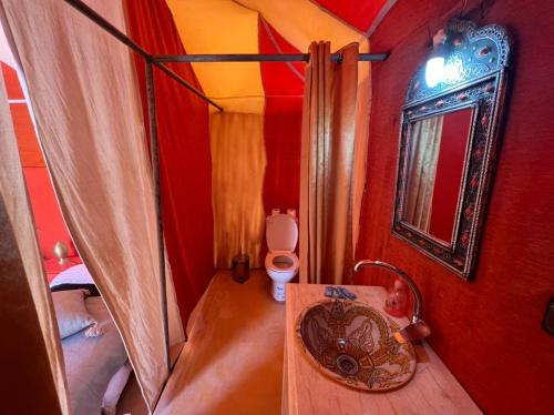 a small bathroom with a toilet and a sink at Candy Camp in Merzouga