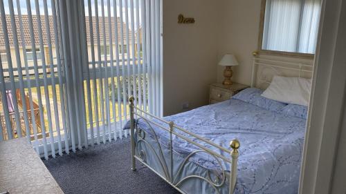 a bedroom with a bed and a large window at 18, Waterside park, Fernly Holiday Home in Corton