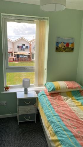 a bedroom with a bed and a window at 18, Waterside park, Fernly Holiday Home in Corton