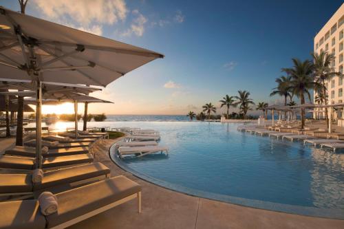 a resort swimming pool with lounge chairs and the ocean at Le Blanc Spa Resort Cancun Adults Only All-Inclusive in Cancún