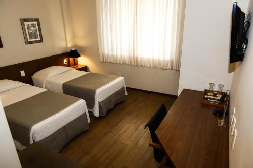 a hotel room with two beds and a table at Timbó Park Hotel in Timbó