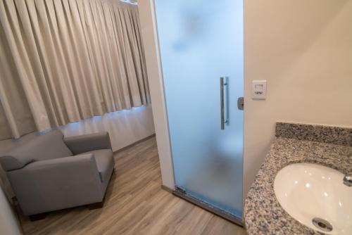 baño con silla y lavamanos en EKO HOTEL en Presidente Prudente