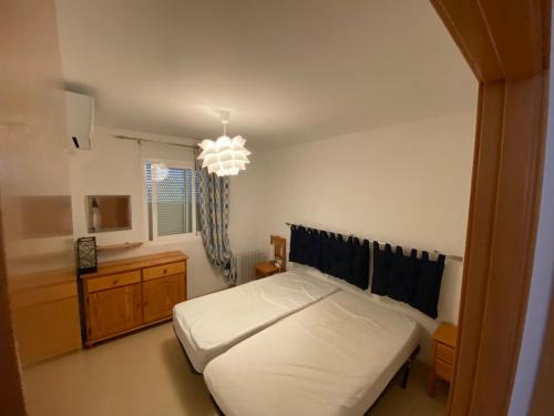 1 dormitorio con cama blanca y lámpara de araña en Apartamentos Punta Canaret Altamar, en Alcossebre
