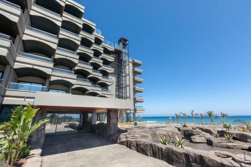 マスパロマスにあるHotel Faro, a Lopesan Collection Hotel - Adults Onlyの海を背景にした海辺の建物