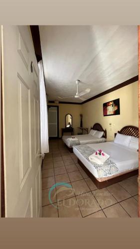 two beds in a room with a door open at Hotel Familiar El Dorado in Zihuatanejo