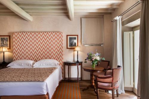 a bedroom with a bed and a table and chairs at Il Borro Relais & Châteaux in San Giustino Valdarno
