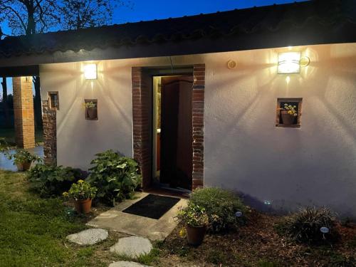 une maison blanche avec une porte et des lumières sur elle dans l'établissement Location gîte 4 personnes Mazères - La Petite Maison, à Mazères