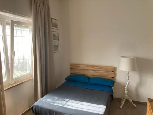 a bedroom with a bed with blue pillows and a window at Il Gelsomino Garden Suite in Sarzana