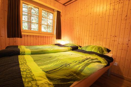 1 dormitorio con 1 cama en una pared de madera en Residenz Edelweiss SAAS320, en Saas-Balen