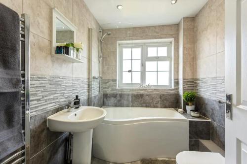 a bathroom with a white tub and a sink and a bath tub at Bright & Spacious with Garden & Parking in Nottingham