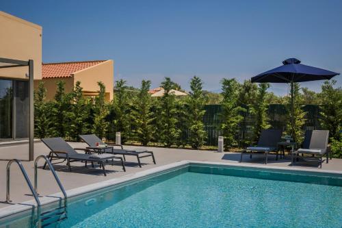 a swimming pool with two chairs and an umbrella at SOUND OF SEA Villas in Lixouri