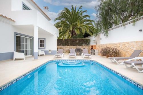 a swimming pool with chairs and a villa at Villa Estrella - Praia da Luz in Luz