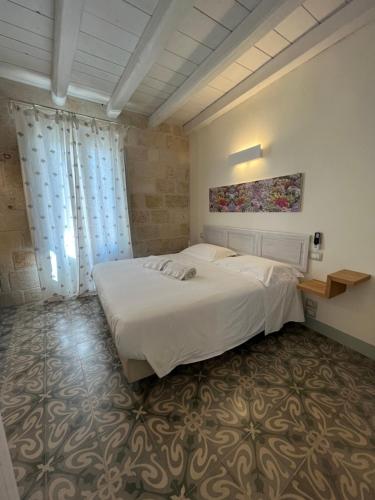 a bedroom with a large white bed and curtains at Antico Mondo Rooms & Suites in Polignano a Mare