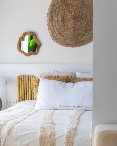 a bedroom with a white bed with a rattan headboard at Hotel de La Plage - Mahogany in Cassis
