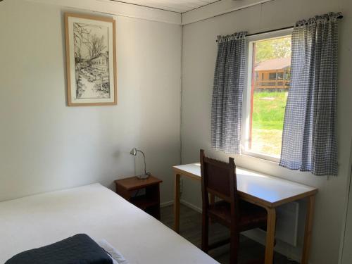 a bedroom with a bed and a desk and a window at Poroholman Lomakeskus in Rauma