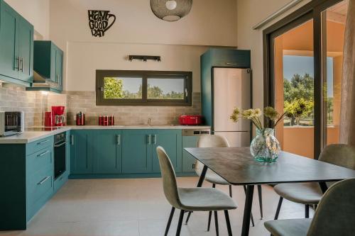 a kitchen with blue cabinets and a table with chairs at SOUND OF SEA Villas in Lixouri