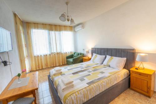 a bedroom with a bed and a table and a chair at Vila Rosen in Lozenets