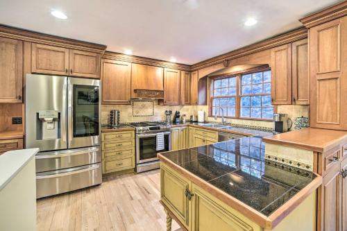 a large kitchen with wooden cabinets and stainless steel appliances at Family-Friendly Retreat with Hot Tub 1 Mi to Dtwn in Saratoga Springs