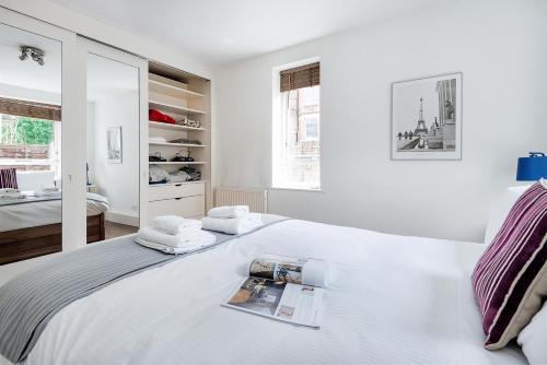 a white bedroom with a bed with towels on it at Bright and stylish apartment in trendy Islington by UnderTheDoormat in London