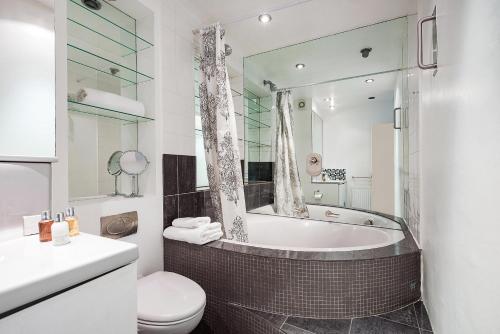 uma casa de banho com uma banheira, um WC e um lavatório. em Bright and stylish apartment in trendy Islington by UnderTheDoormat em Londres