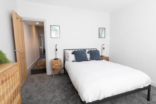 um quarto com uma grande cama branca com almofadas azuis em The Hideout - free parking em Southampton