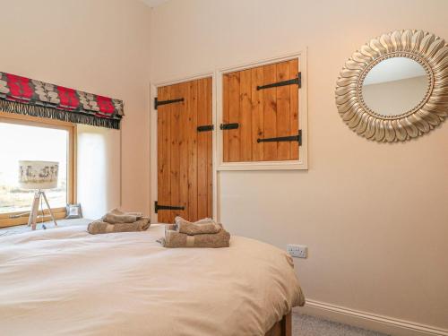 a bedroom with a bed with a mirror and a window at Columbine Barn in Bradwell